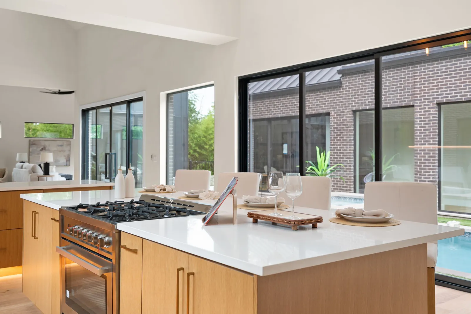 Custom kitchen island with pool view by CBA Design & Build