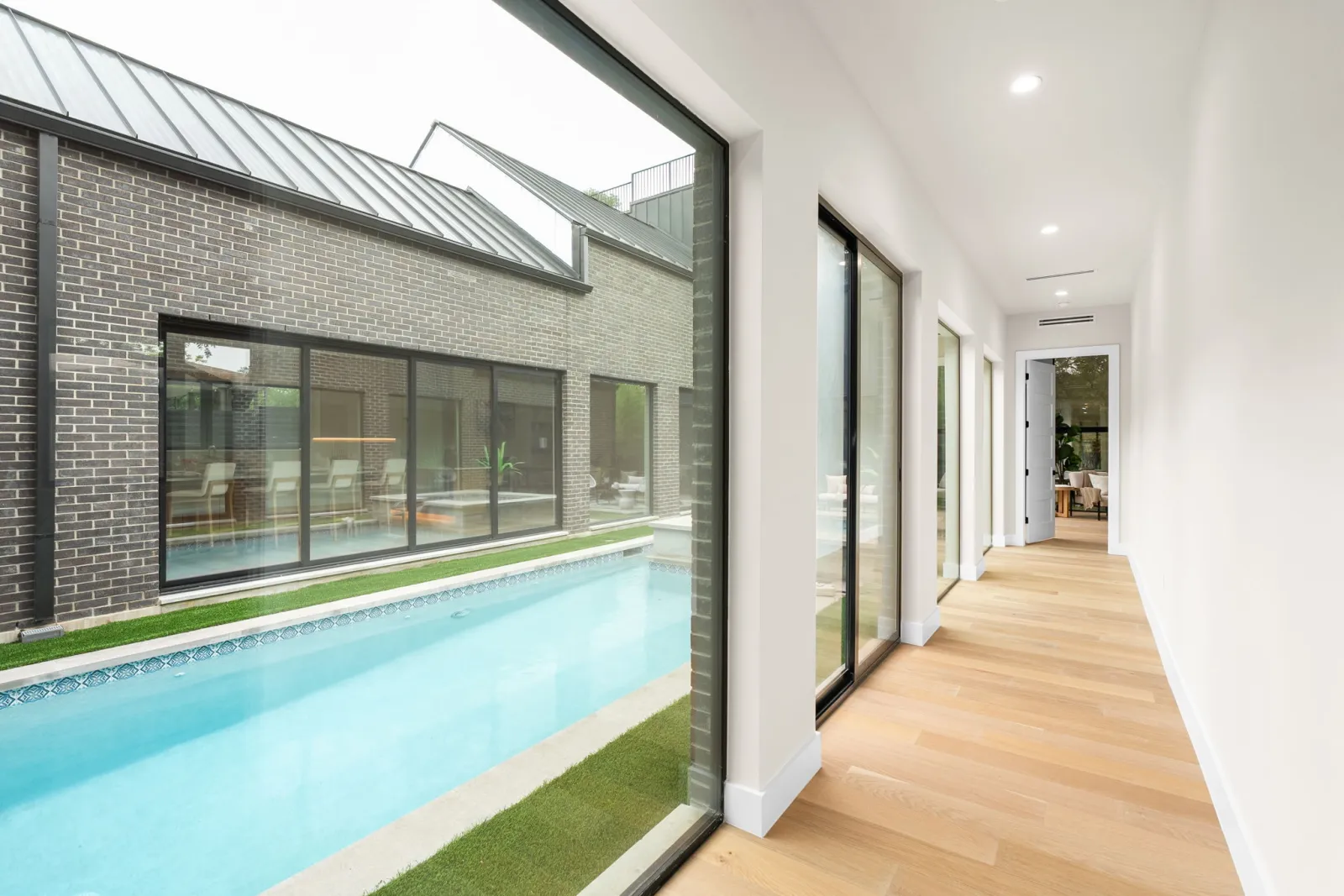 Glass-lined hallway alongside the courtyard lap pool of a CBA Design & Build home